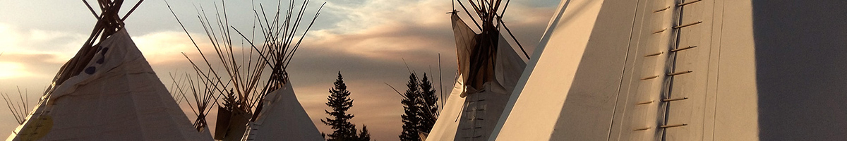 Banner image with teepees under a sunset