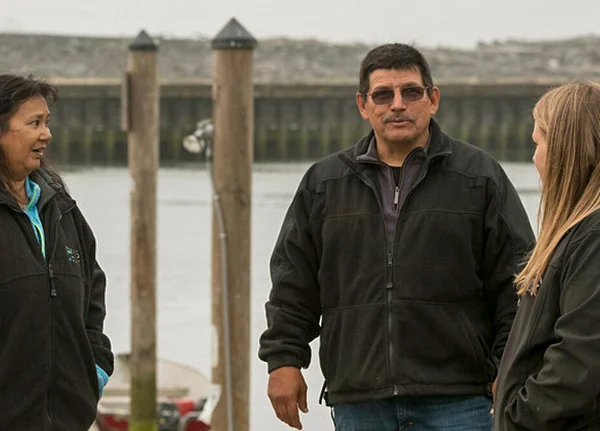 Three people talking on a dock