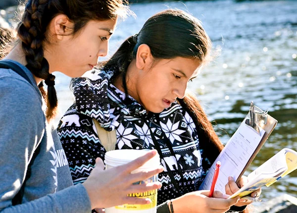 Two young people looking at clipboard with paperwork
