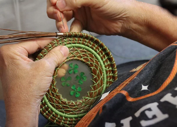 Person using a traditional coiling technique to make pine needle baskets