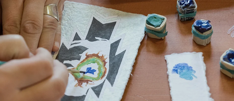 Hands painting a tribal design with watercolors
