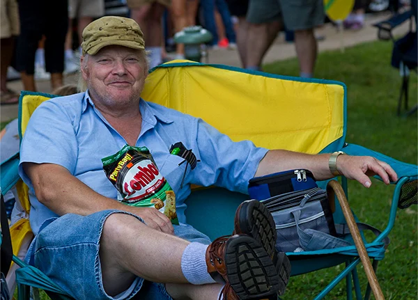 Man wearing a hat and sitting in a camping chair with his legs propped up