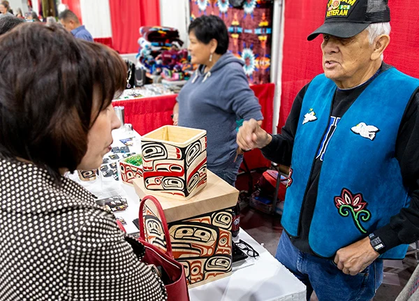 Man selling boxes with tribal designs at a craft fair booth