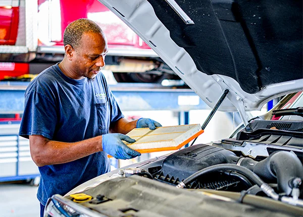 Mechanic holding an air filter as he works on a vehicle