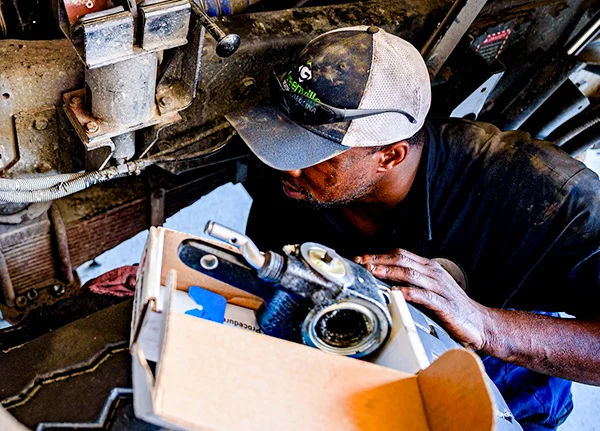 Mechanic kneeling down, inspecting something