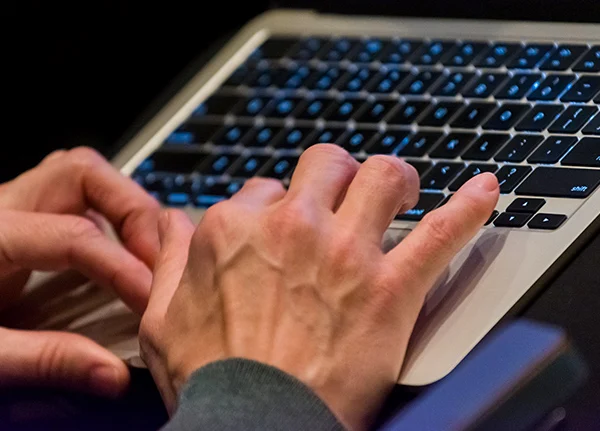 Hands typing on a laptop