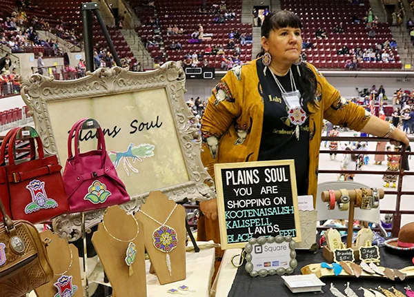 Woman standing at a booth at in indoor powwow