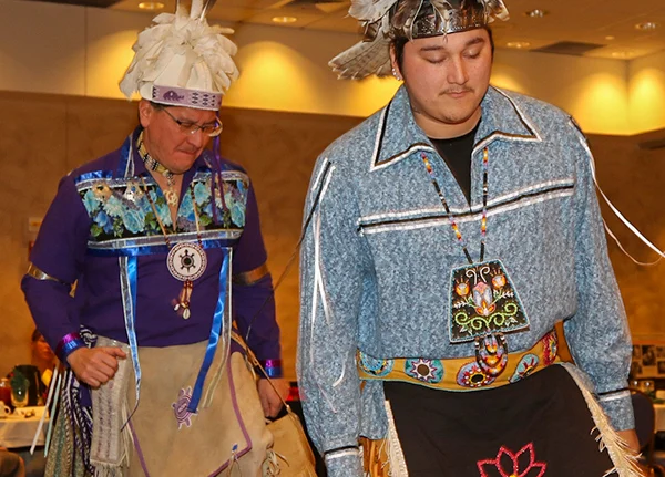 Two dancers wearing ribbon shirts