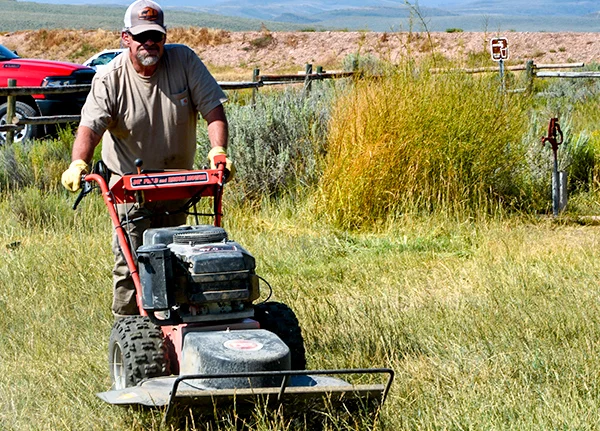 Man pushing industrial lawn mower