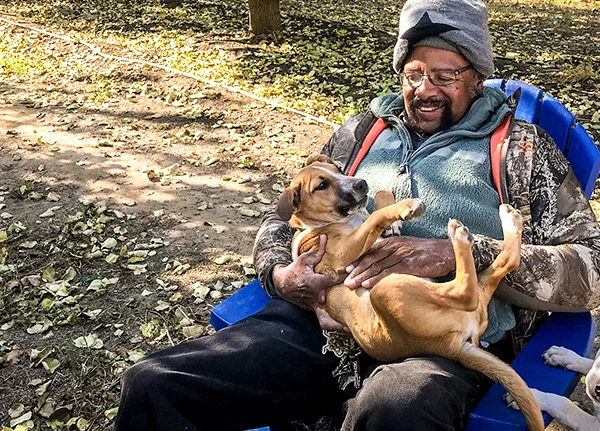 Man sitting in chair petting a dog in his lap