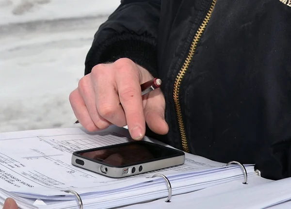Person holding a binder full of paperwork with a phone on top