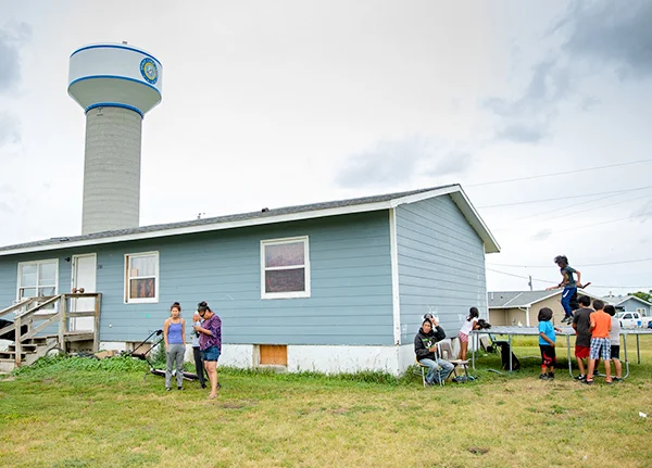 House in a rural area with a large family and kids jumping on a trampoline