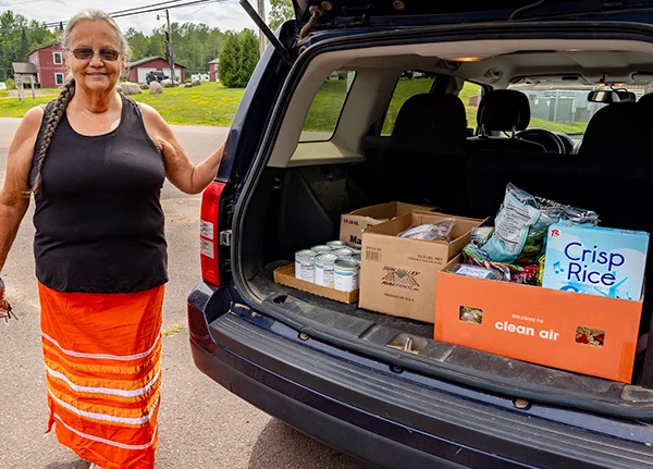 Woman standing next to a vehicle with groceries loaded in it