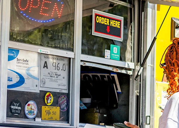 Food truck with sanitation rating sign and ServSafe Certification in the order window