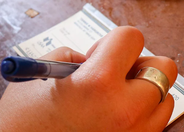 Hand holding a pen and filling out a check