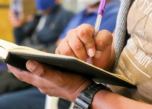 Hand holding a pen and writing in a notebook