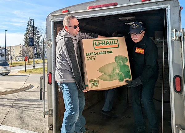 Two men carrying a large box out of a trailer