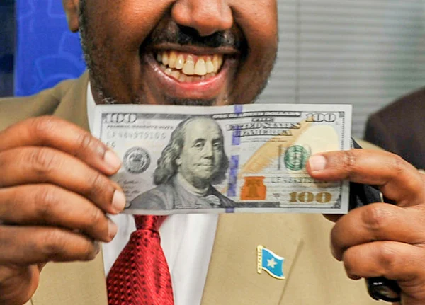 Man smiling and holding a one hundred dollar bill