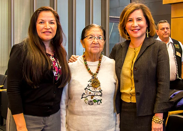 Three women smile and pose for the camera