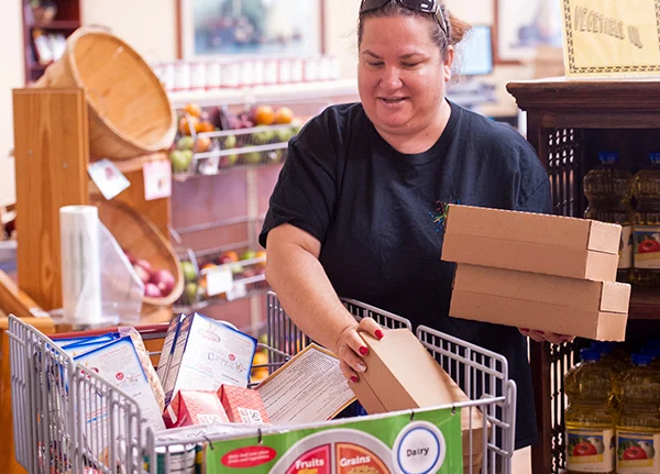 Woman in grocery store putting boxes in a full cart