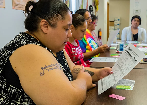 Woman sitting at a table looking at a piece of paper