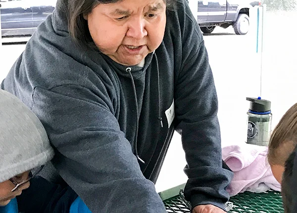 Woman leaning over a table pointing to something out of frame