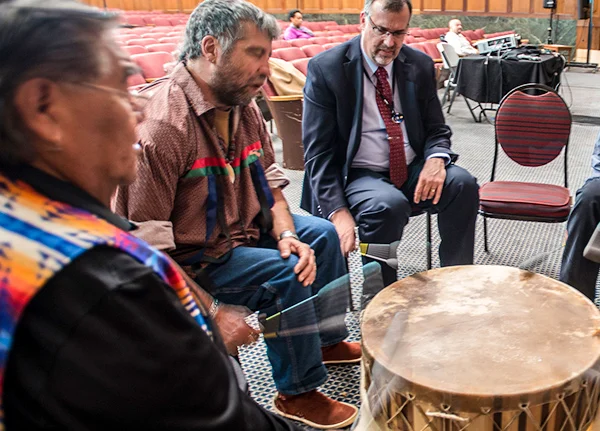 A group of people beat a drum at an indoor event