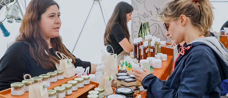 Woman looking at a product for sale at a booth while talking to the vendor