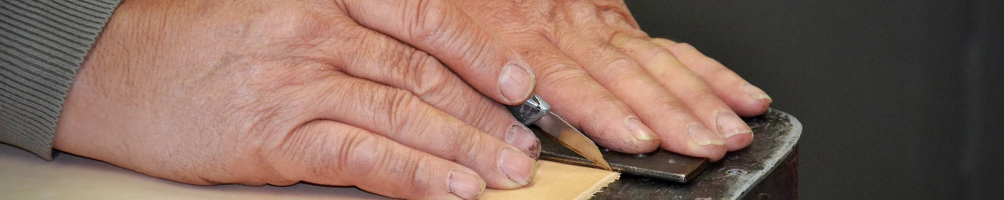Hands using an Exacto knife to cut leather