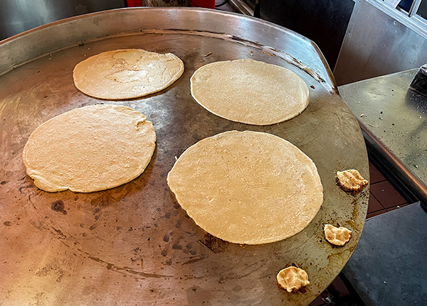 Tortillas cooking on a large flat-top griddle