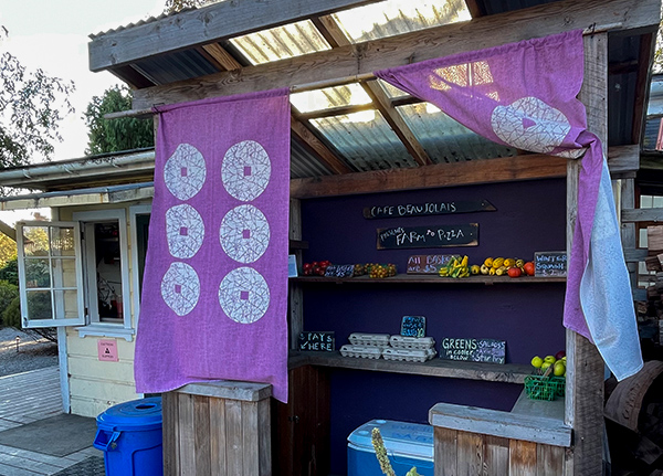 A small booth in front of a business with eggs and other fresh veggies for sale