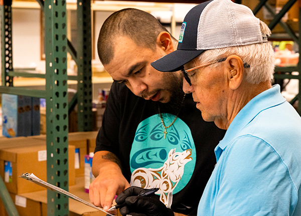 Two men standing next to each other looking at something on a clipboard