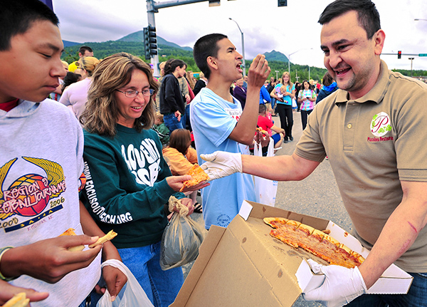 Man handing out pizza slices at a parade