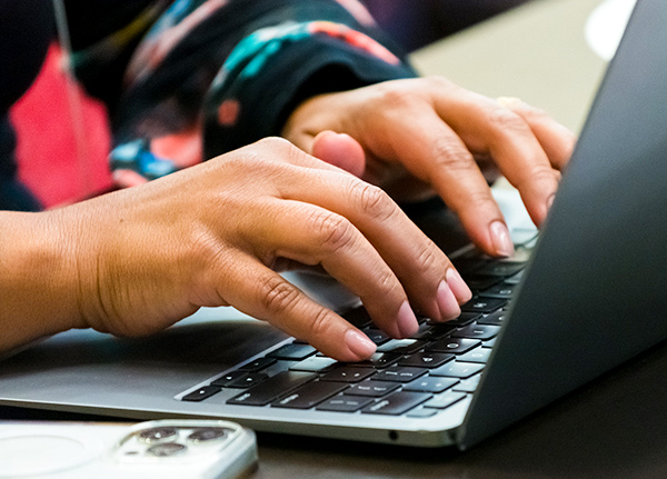 Hands typing on a laptop keyboard