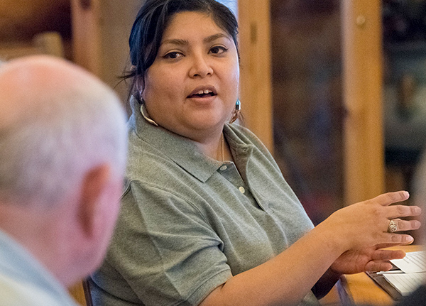 A woman sits at a table talking to a man next to her