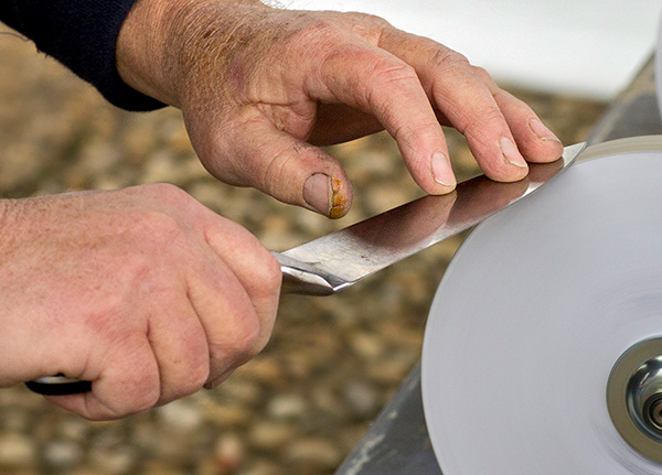 Close up of hands sharpening a knife blade