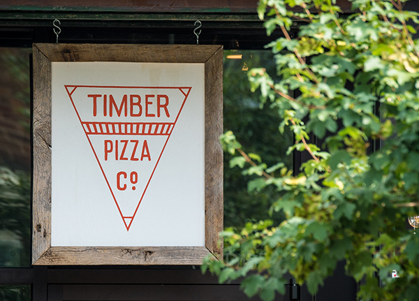 Sign hanging from a business that reads Timber Pizza Co.