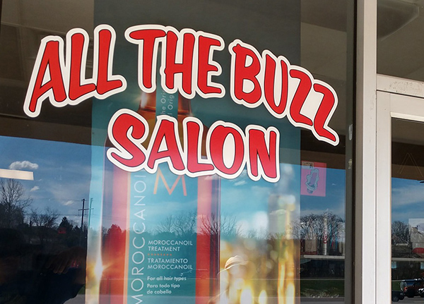 Window with a decal that says All the Buzz Salon