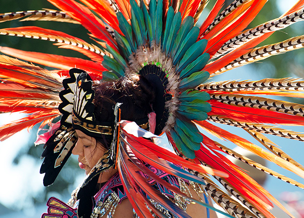Woman dancing at a powwow with a large, ornate feathered headdress