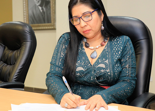 Woman sitting at a conference table writing on a piece of paper