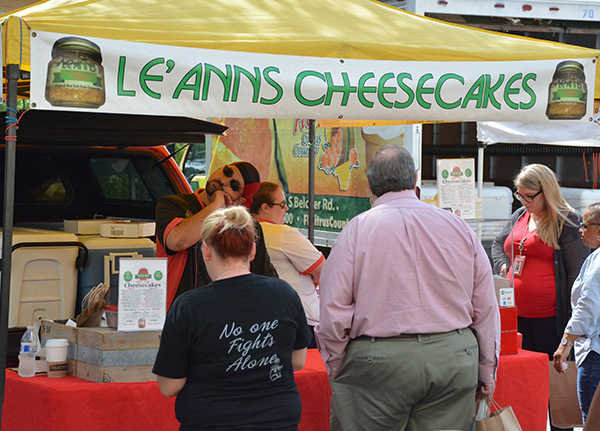 People standing at an outdoor vending stand that says Le'Ann's Cheesecakes