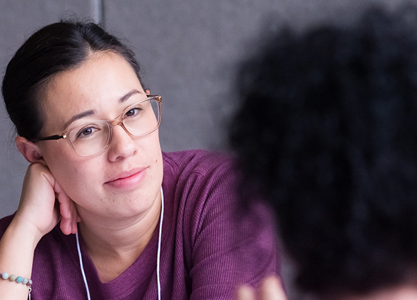 Woman resting her head on her hand while listening to someone across from her