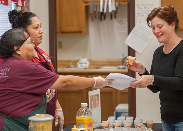 Two women giving out samples of a juice drink