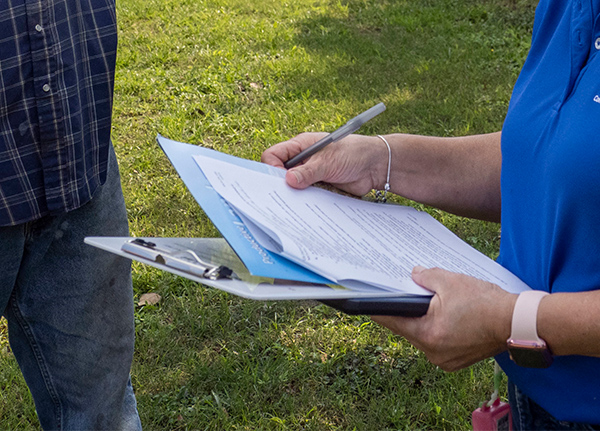 Person filling out paperwork on a clipboard
