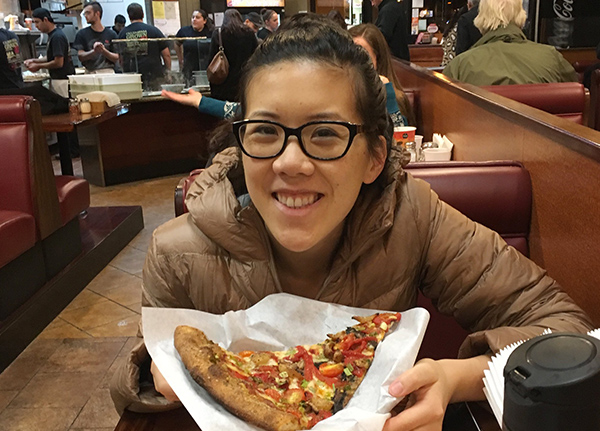 Young woman smiling with a piece of pizza