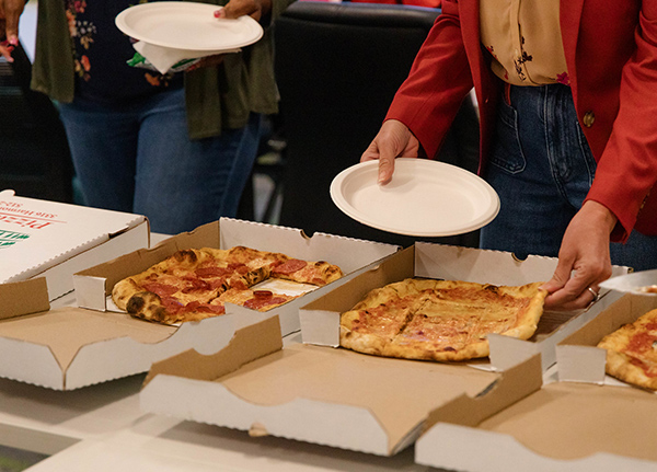 People grabbing pizza from pizza boxes
