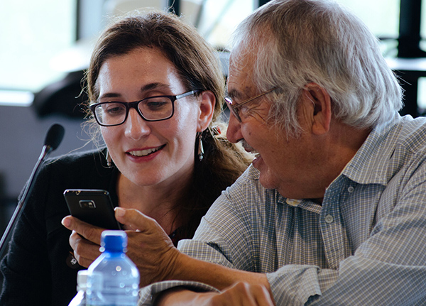 Two people sitting next to each other looking at something on a phone