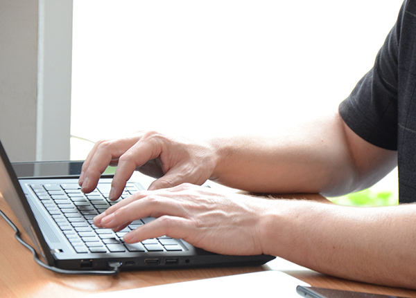 Hands typing on a laptop