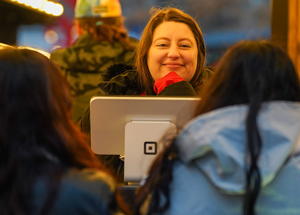 Woman standing behind a Square point of sales system with a smile