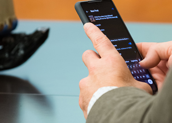 Hands typing a social media post on a phone
